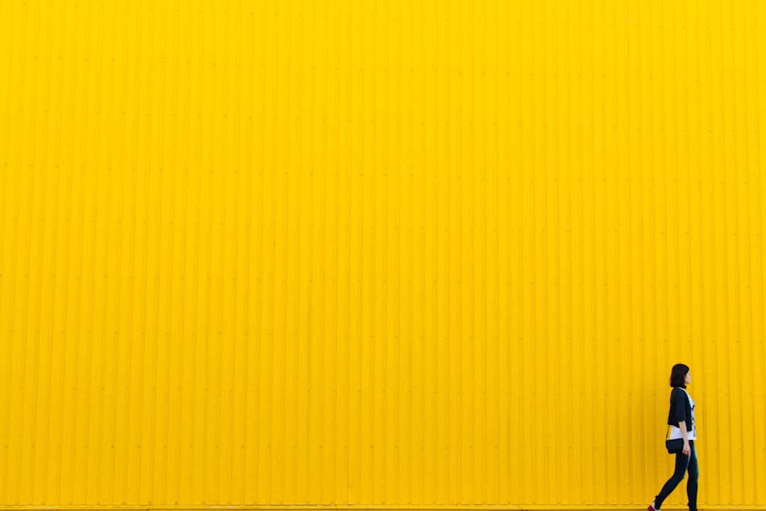 Person walking past a bright yellow wall, symbolizing creativity and bold design choices in website development.